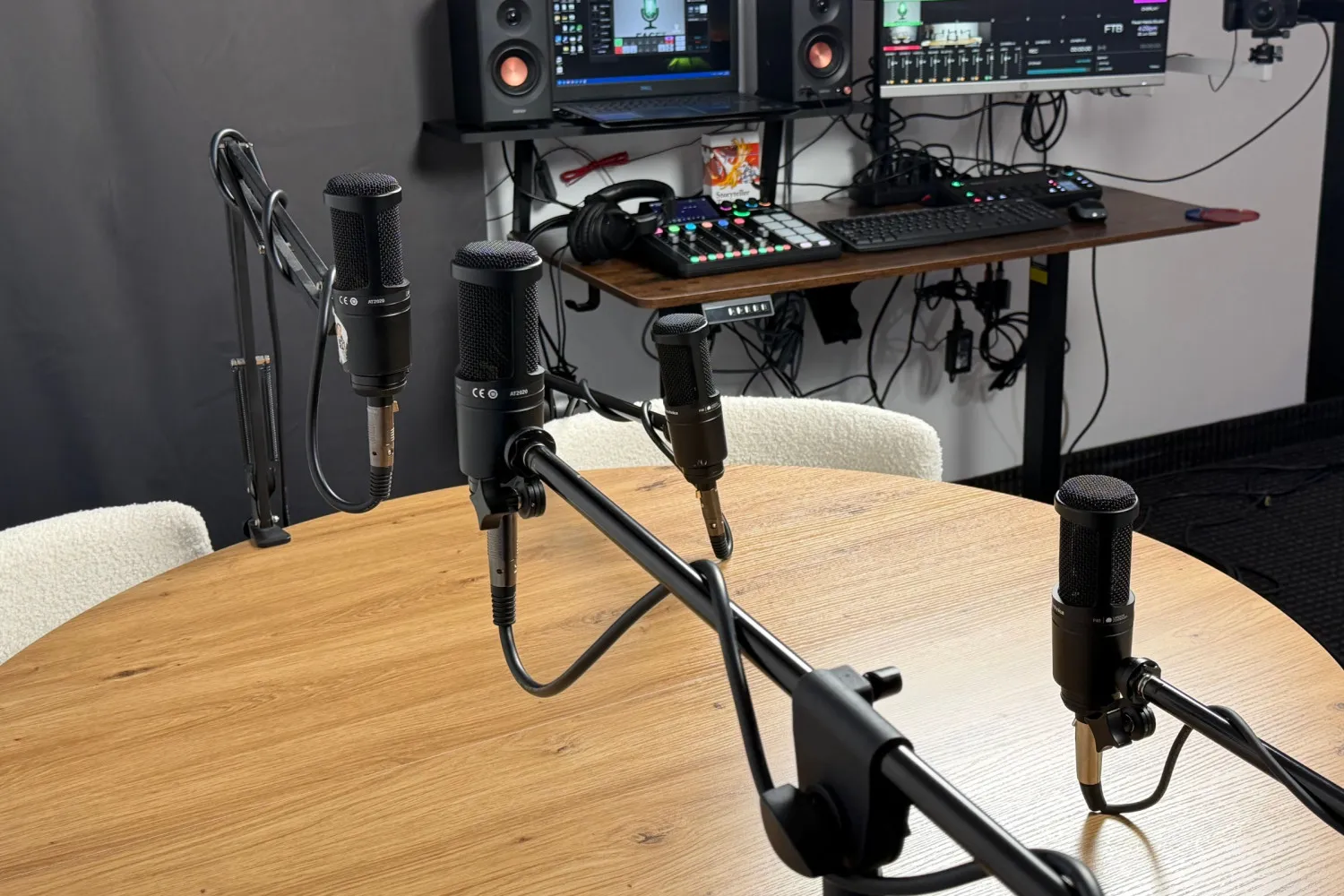Four black microphones on a round wooden table.