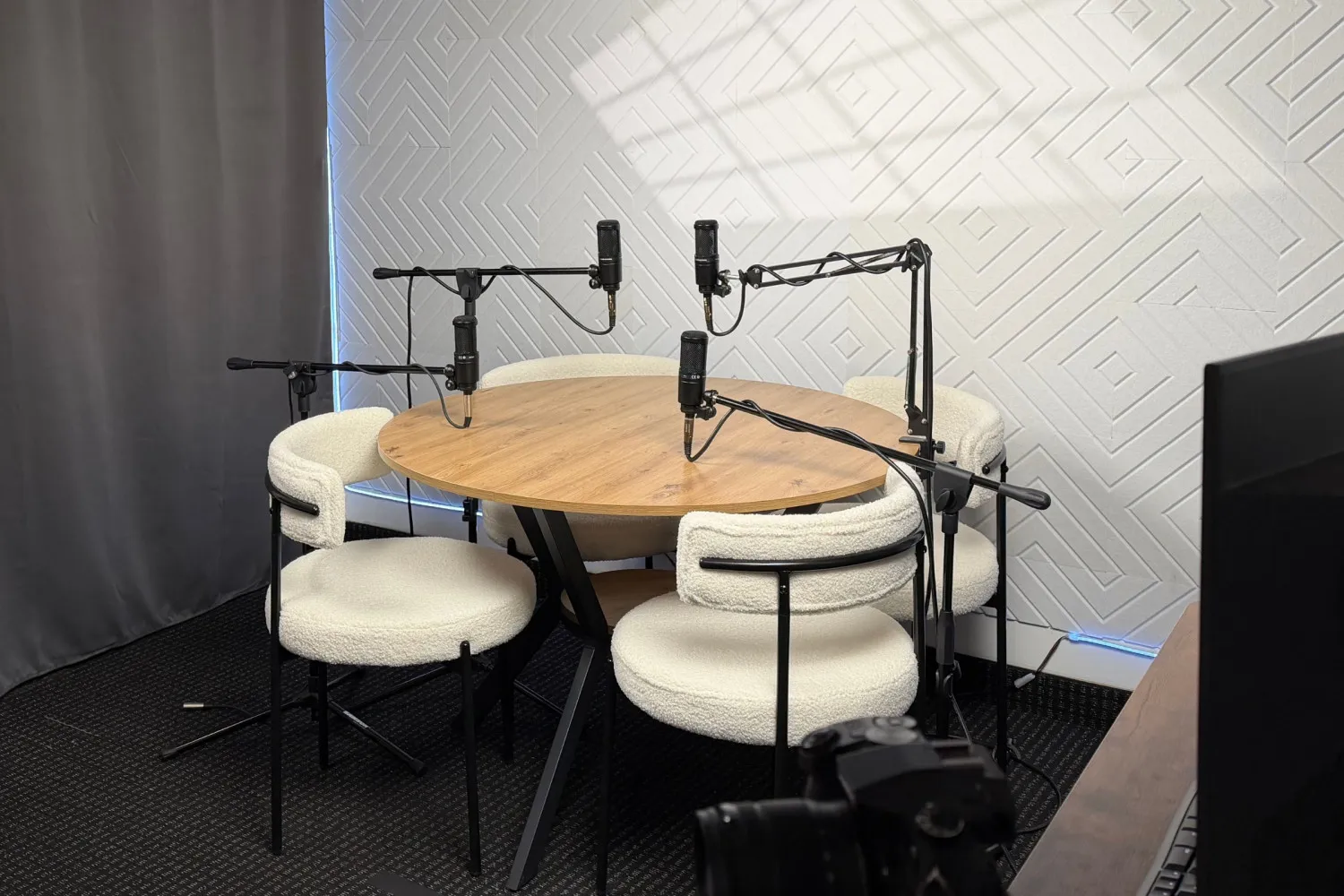 Podcast table with four white chairs and mics.