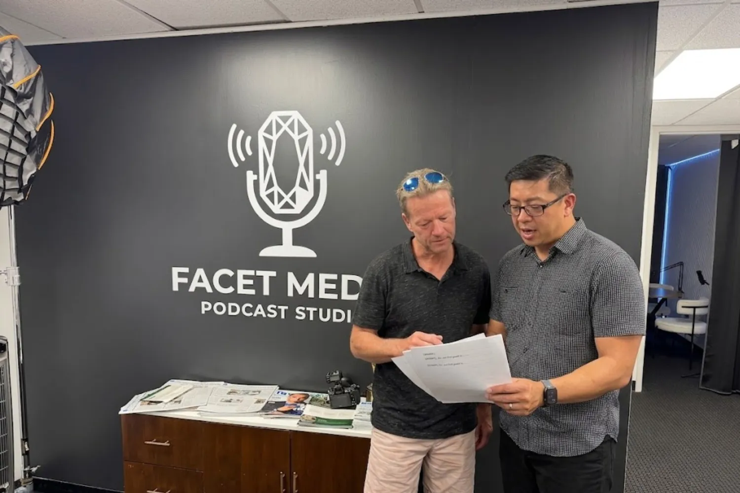 Two men reading a document at a podcast studio