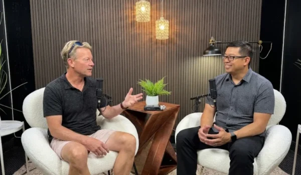 Two men talking into microphones during a podcast